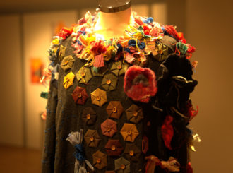Aufnahme eines Pullovers aus der Ausstellung Ugly Sweater, der mit verschiedenen Textilresten ausgestattet ist